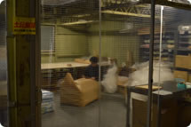 ホコリなど遮断するカーテンで仕切られた作業スペースで梱包します。
