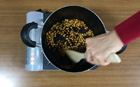 豆が一粒弾けたらすぐにキャラメルフレーバーを入れ、木べらでかき混ぜフタをします。